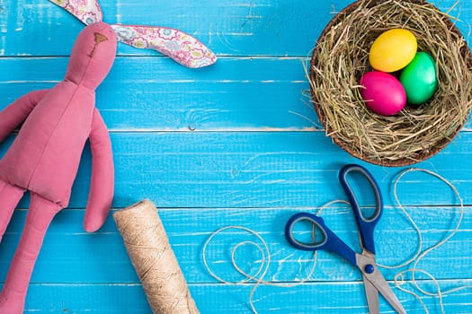 Colorful easter egg in nest on blue wood board. Background for room or space for copy, text, words.