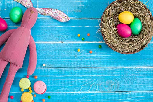 Colorful easter egg in nest on blue wood board. Background for room or space for copy, text, words.