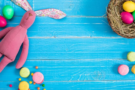 Colorful easter egg in nest on blue wood board. Background for room or space for copy, text, words.
