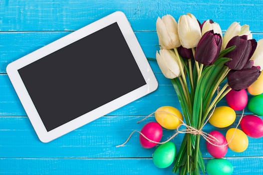 Easter eggs and tulips on blue rustic wooden planks. Still life. Top view. Copy space