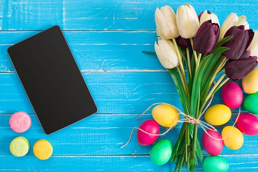 Easter eggs and tulips on blue wooden planks. Top view. Copy space