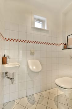 a bathroom with red and white tiles on the walls, toilet bowl, sink basin and mirror in the corner