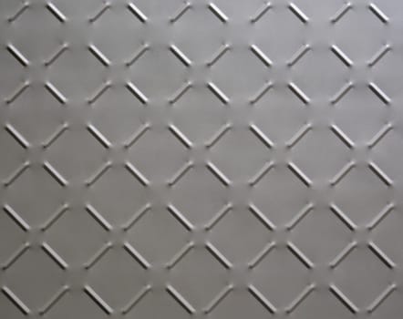 abstract background of metal plate with diamond pattern painted grey close up.