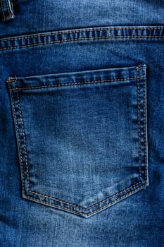 Casual wear. Classic blue woman jeans with empty back pocket as background. Denim fabric for tailoring. Vertical top view. Comfortable style cloth.