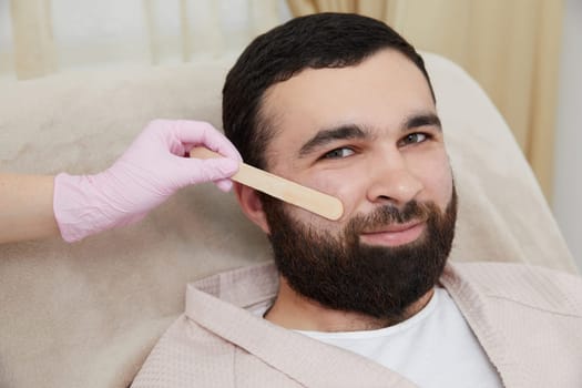 Bearded man getting laser facial treatment by professional cosmetologist in a beauty clinic. Healthy man lifestyle concept