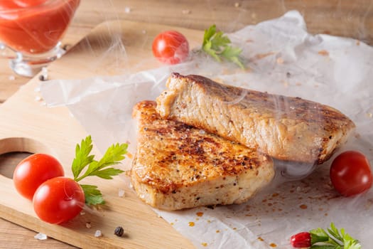 Slices of roast pork meat with tomato and ketchup on a wooden board