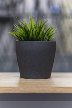 Green artificial grass with a lot of plastic stems in gray concrete flower pot