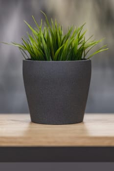 Green artificial grass with a lot of plastic stems in gray concrete flower pot