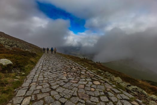 Long stony mountain trail over Sniezka mountain in Giant mountains with beautiful cloudy green landscape around