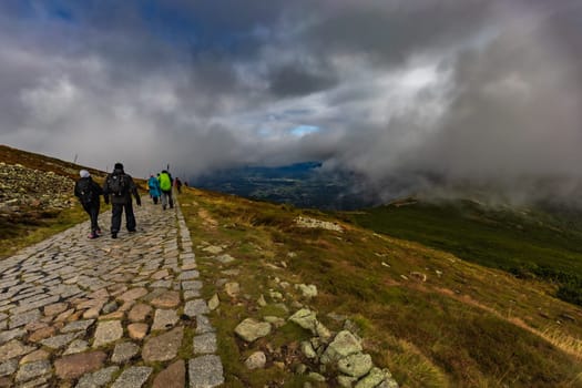 Long stony mountain trail over Sniezka mountain in Giant mountains with beautiful cloudy green landscape around