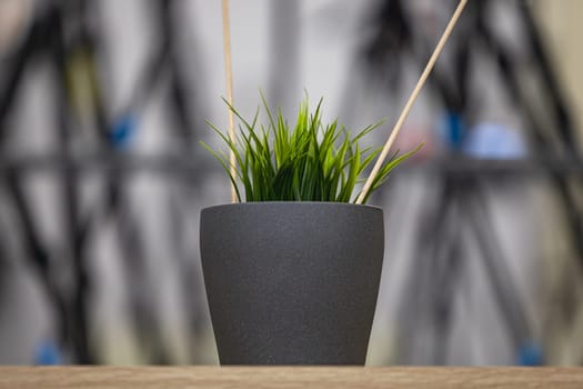 Green artificial grass with a lot of plastic stems in gray concrete flower pot