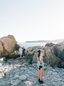 Girl-photographer takes pictures of men standing on the rocks by the sea. High quality photo