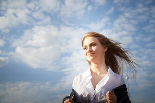 Portrait of Beautiful girl with long blonde hair in white shirt and jacket in village or small town. High young slender woman in an autumn, spring, summer day and blue sky on background