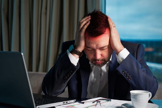 Tired man working at home office, Exhausted, stressed, overworked man, financial market decline, unsuccessful investments. tension headache. Sad businessman lying on laptop.