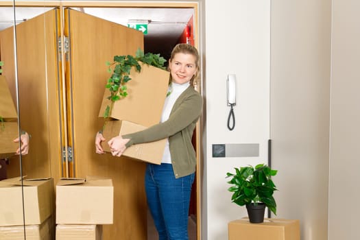 Happy young single woman moving to new home. Having fun in moving day. Woman carrying moving boxes. Successful Woman with belongings in cardboard boxes on moving day
