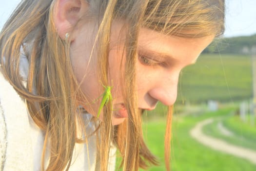 Romantic shot of a blonde girl with a grasshopper in her hair