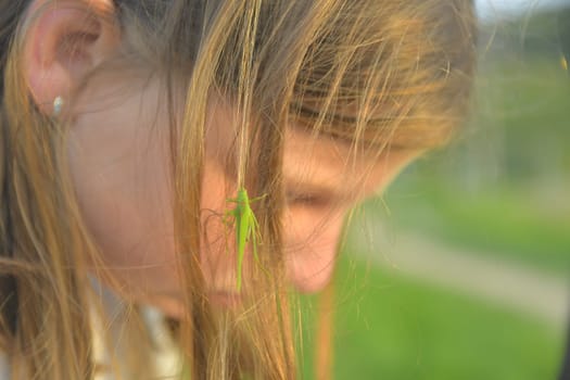Romantic shot of a blonde girl with a grasshopper in her hair