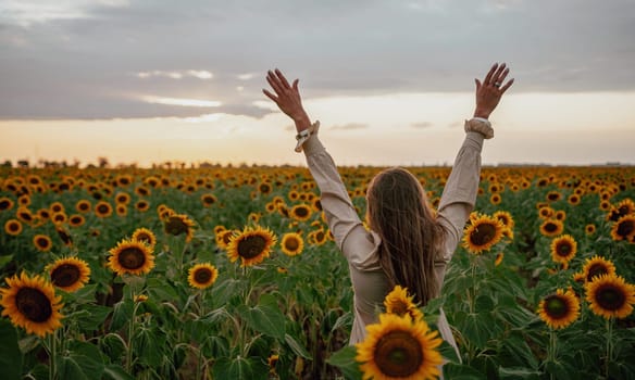 Woman in the sunflowers field. Summer time. Young beautiful woman standing in sunflower field.