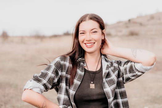 Happy young smiling woman with freckles outdoors portrait. Soft sunny colors. Outdoor close-up portrait of a young brunette woman and looking to the camera, posing against nature background.