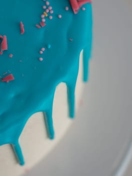 studio shot of chocolate frosted blue dripped icing white cup cake, unicorn , meringue and sprinkles on top