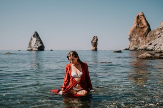 Woman travel sea. Happy tourist taking picture outdoors for memories. Woman traveler looks at the edge of the cliff on the sea bay of mountains, sharing travel adventure journey.