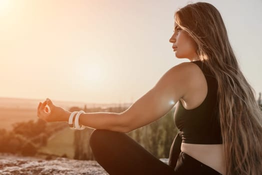 Well looking middle aged woman with long hair, fitness instructor in leggings and tops doing stretching and pilates on the rock near forest. Female fitness yoga routine concept. Healthy lifestyle.