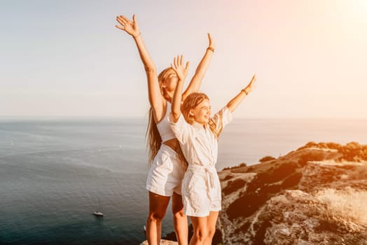 Close up portrait of mom and her teenage daughter hugging and smiling together over sunset sea view. Beautiful woman relaxing with her child.