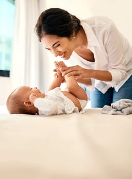 Smile, love and a mother with her baby in the bedroom of their home together for playful bonding. Family, kids and a happy young mama spending time with her newborn infant on the bed for fun or joy.