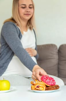 A pregnant woman eats a sweet donut. Selective focus. Food.