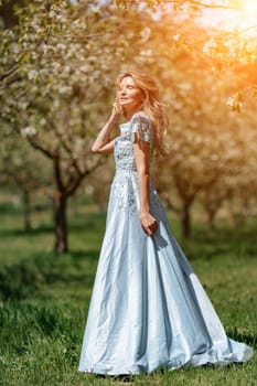 Portrait of a blonde in the park. Happy woman with long blond hair in a blue dress