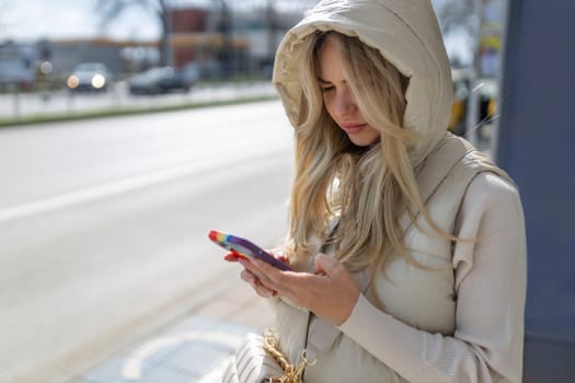 Cheerful female tourist using mobile phone for view map via network and continue her walk in strange city, beautiful hipster girl in good mood consult bus schedule via internet on her cell telephone .