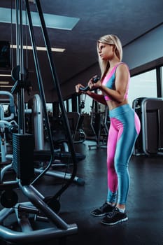 Young fitness woman execute exercise with exercise-machine Cable Crossover in gym. Vertical photo. Muscular