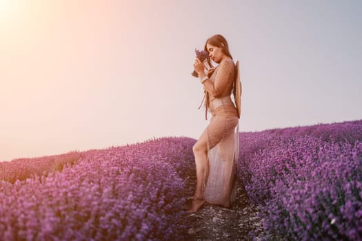 Close up portrait of young beautiful woman in a white dress and a hat is walking in the lavender field and smelling lavender bouquet.