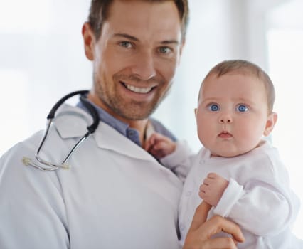 Portrait, happy pediatrician and holding baby in hospital for medical support and growth. Newborn kid face, man and pediatrics doctor in clinic, healthcare service or smile of trust for children.