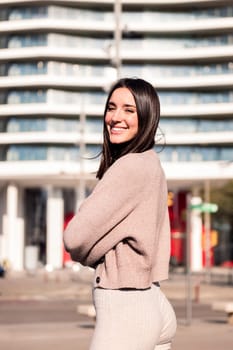 young woman smiling looking at camera on sunny morning at city, concept of happiness and urban lifestyle, copy space for text