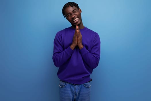 charming dark-skinned young brunette man with dreadlocks in a blue sweatshirt.