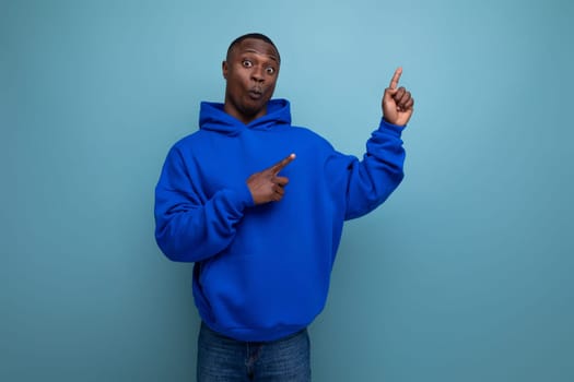 authentic ethnic young african man in stylish hoodie on blue background.