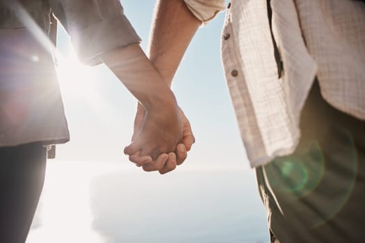 Love, unity and couple holding hands on the beach while on a date for romance or their anniversary. Trust, support and closeup of man and woman with hand intimacy and affection while on outdoor walk