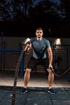 Young man in sportswear training with ropes. Athlete Outdoors