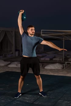 Muscular man working with weights at outdoor. sport exercises with kettlebell. street workout