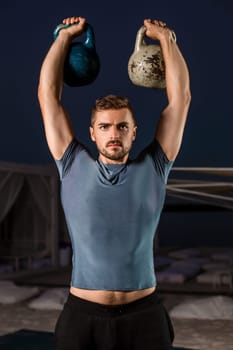 Muscular man working with weights at outdoor. sport exercises with kettlebell, street workout