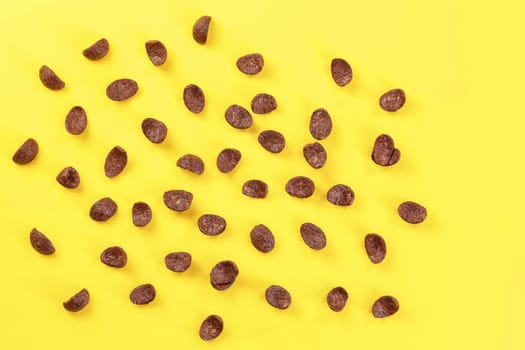 Top down view, chocolate cornflakes scattered on yellow board.