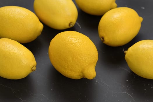Ripe lemons on black marble board.