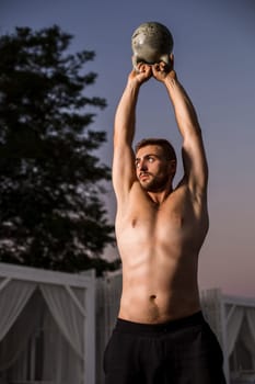 Muscular man working with weights at outdoor. sport exercises with kettlebell. street workout