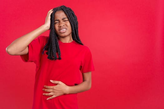 African woman gesturing bodily discomfort and headache in studio with red background