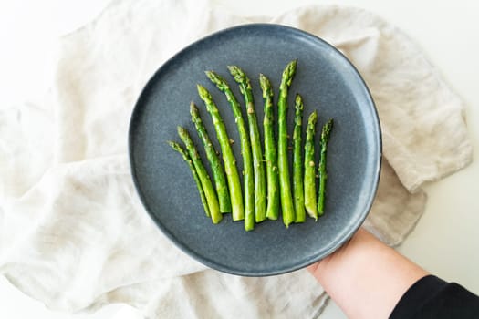 Close-up on a large plate - asparagus with salt and garlic. Delicious and healthy food served in a restaurant, beautifully served by the chef