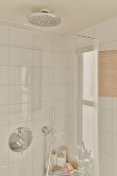 a bathroom with white tiles on the walls, and a shower head mounted in the corner of the bathtub