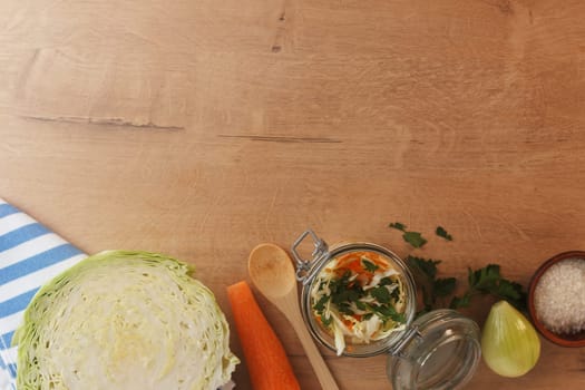 Cabbage lies on a wooden board with carrots, onions and herbs. Preparing to cook cabbage dishes.Copy space