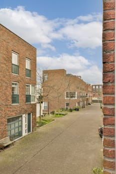 a brick building in the middle of an urban area with trees and buildings on both sides, along a paved street