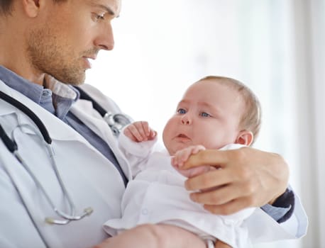 Doctor, sick and sad baby in clinic for healthcare assessment, pediatrics support and help. Pediatrician holding unhappy newborn kid for hospital service, medical test and wellness of crying children.